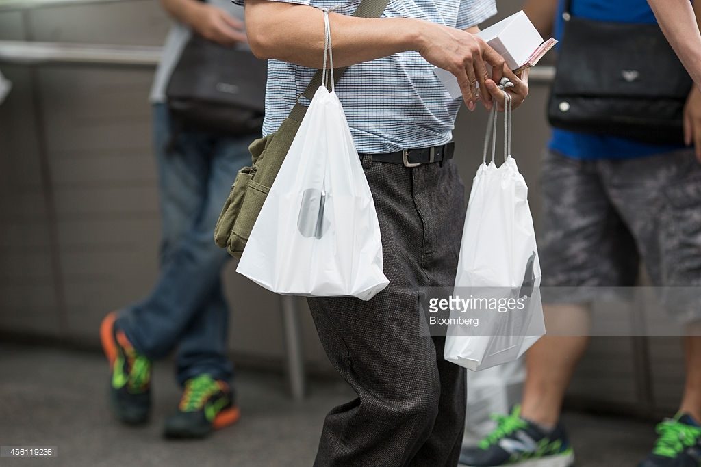 A man holds plastic bags containing boxed Apple Inc. iPhones 6 and 6 Plus and Hong Kong dollar bills as he tries to resell the devices outside the company's Central district store in Hong Kong, China, on Friday, Sept. 26, 2014. Photographer: Jerome Favre/Bloomberg